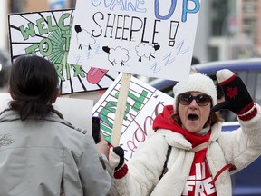 A lone pro-vaccine mandate protester (left) and an anti COVID-19 health measures protester (right) have words near the Alberta Legislature in Edmonton on Saturday Feb. 12, 2022.