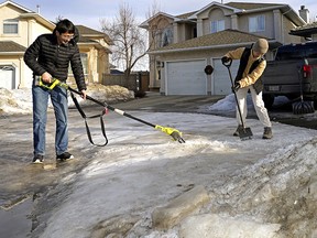 Yunsook Lee and her husband Jae Cho try to remove the ice from the sidewalk and driveway in front of their home in southwest Edmonton on Thursday February 10, 2022.