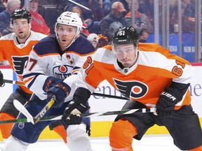 Justin Braun (61) of the Philadelphia Flyers and Connor McDavid (97) of the Edmonton Oilers skate after the puck at Wells Fargo Center on March 1, 2022, in Philadelphia.