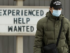 A pedestrian makes their way past a help wanted sign at a Jiffy Lube location, 9927 82 Ave. in Edmonton on March 15, 2022.