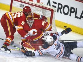 Oilers defenceman Brett Kulak (27) crashes into the net in front of Calgary Flames goalie Jacob Markstrom and Noah Hanifin in Calgary on Saturday, March 26, 2022.