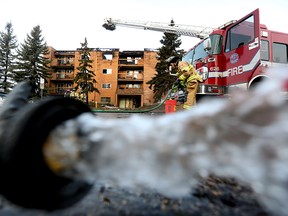 A fire hose is visible in the foreground as firefighters continue to work at the scene of a fire at the Erindale condominiums, 9504 182 St., in Edmonton, Wednesday, March 31, 2022.