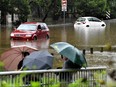 Residents watch submerged cars in floodwaters in southwestern suburb of Sydney on March 8, 2022, as thousands of Sydneysiders have been asked to evacuate from the low lying areas due to heavy rain and flash floodings.
