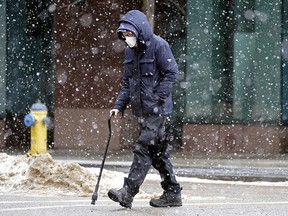 A man crosses the street in downtown Edmonton on Monday March 7, 2022 amid snow flurries and wind gusts of 40 km/hour. (PHOTO BY LARRY WONG/POSTMEDIA)