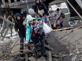 Residents of Irpin near Kyiv, Ukraine, flee heavy fighting via a destroyed bridge as Russian forces entered the city on March 07, 2022.