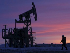A worker walks past a pump jack on an oil field owned by Bashneft company near the village of Nikolo-Berezovka, northwest from Ufa, Bashkortostan, Russia, January 28, 2015.
