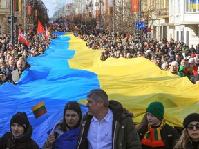 People walk with a giant many metres-long Ukrainian flag to protest against the Russian invasion of Ukraine during a celebration of Lithuania's independence in Vilnius, Lithuania, on March 11, 2022.