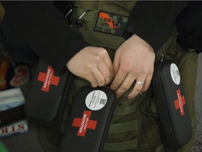 A "I run into the fire" patch is visible as Raye Cameron straps naloxone kits to his backpack as volunteers with Boots On Ground prepare to walk the underground pedway system in downtown Edmonton on Feb. 22, 2022. Boots on Ground is a harm reduction organization that hands out naloxone kits, safe supplies and provides education on safe use.