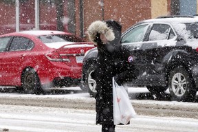 El domingo 20 de marzo de 2022, un comerciante camina sobre la nieve en White Avenue en Edmonton.