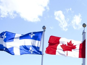 The Canadian and Quebec flags are seen over looking the Ottawa River from the Civilization Museum behind Parliament Hill in Gatineau. File photo.