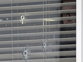 A police officer examines the bullet holes in the window at a residential home located at 374 Heath Road in the southwest Edmonton neighborhood of Riverbend on Monday March 14, 2022.