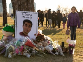 Family and friends stand in silent vigil at a memorial outside the school on Friday, April 29, 2022, for Karanveer Sahota, who was stabbed to death outside McNally High School.