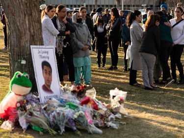 Family and friends stand in silent vigil at a memorial for Karanveer Sahota, who was beaten and stabbed to death outside McNally High School, during a vigil outside his school in Edmonton, on Friday, April 29, 2022.