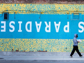 A pedestrian wearing a mask walks past upside down writing saying “This Is Paradise” outside of Toronto’s The Cameron House during the Covid 19 pandemic.[Peter J Thompson/National post]