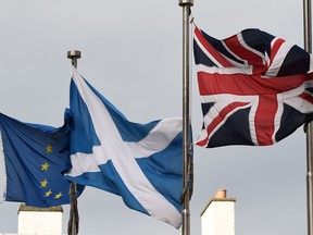 A Scottish Saltire (C) flies between a Union flag (R) and a European Union (EU) flag, in front of the Scottish Parliament building in Edinburgh.