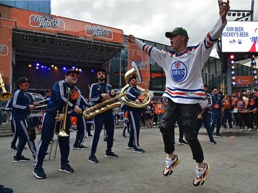 A jubilant fan leaps into the air as the Oilers Drum and Brass Crew performs for fans at the tailgate party in the ICE district Plaza prior to the start of the Oilers game two against the LA Kings in Edmonton, May 4, 2022.