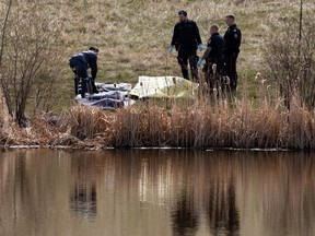 Edmonton Police Service officers and a coroner from the Office of the Medical Examiner respond after a body was found in a storm pond near 153 Avenue and Manning Drive in Edmonton, on Wednesday, May 11, 2022.