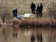 Edmonton Police Service officers and a coroner from the Office of the Medical Examiner respond after a body was found in a storm pond near 153 Avenue and Manning Drive in Edmonton, on Wednesday, May 11, 2022.