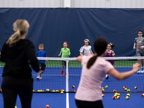 Children play a game of ball tennis with their instructors during the grand opening of the club's $7 million indoor tennis center with 4 state-of-the-art plexicushion courts in Edmonton, Sunday, May 15, 2022.