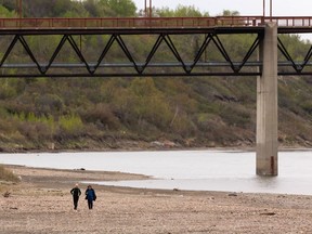 Friends will take a walk on the beach of the North Saskatchewan River near Edmonton's Cloverbar Pedestrian Bridge on Wednesday, May 18, 2022.
