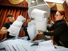 Members of a local electoral commission empty a ballot box at a polling station after the last day of the three-day parliamentary election, in Moscow, on September 19, 2021.