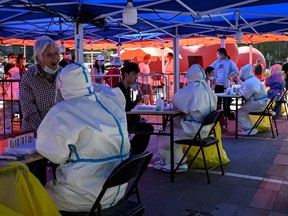 A health worker takes a swab sample from an elderly woman to be tested for Covid-19 at a makeshift testing site outside a museum along a street in Beijing on May 4, 2022.