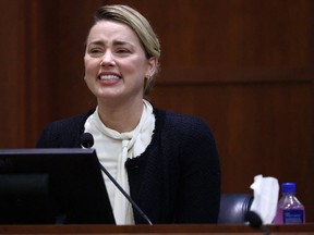 Amber Heard chokes back tears on the stand at Fairfax County Circuit Court during a defamation case against her by ex-husband, Johnny Depp, May 5, 2022.