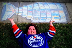 Laurie Keindel, a Devon resident, poses under her sidewalk artwork representing the Stanley Cup.  We hope to see someone in an Oilers jersey lifting the royal cup soon….