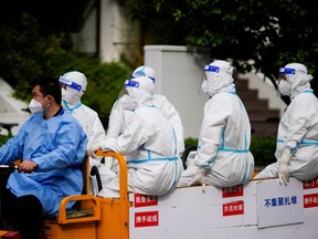 Workers in protective suits ride an electric tricycle on a street during lockdown, amid the COVID-19 pandemic, in Shanghai, China, Sunday, May 1, 2022.