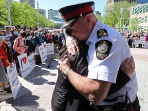 Edmonton Police Chief Dale McFee hugs Dr. Holly Mah, Chair of Chinatown and Area Business Association, as they take part in a Chinatown safety rally outside City Hall, in Edmonton Saturday May 28, 2022.