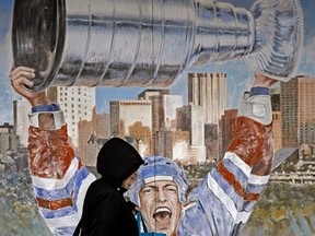 A woman walks past a mural of former Edmonton Oiler Mark Messier hoisting the Stanley Cup outside the Old Strathcona Antique Mall in Edmonton on Friday May 6, 2022, perhaps a sign of things to come.
