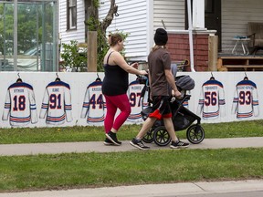 People walk by a fence with new boards screwed over the old ones with Edmonton Oilers uniforms on them in the Oliver neighbourhood at 11648 102 Ave on Friday, May 27, 2022 in Edmonton.  Greg Southam-PostmediaPeople walk by a fence freshly painted with Edmonton Oilers uniforms in the Oliver neighbourhood at 11648 102 Ave on Friday, May 27, 2022 in Edmonton. Greg Southam-Postmedia