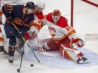 Edmonton Oilers Connor McDavid (97) battles with Calgary Flames Noah Hanifin (55) in front of goaltender Jacob Markstrom (25) during first period NHL second round playoff hockey action  on Sunday, May 22, 2022 in Edmonton.