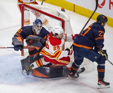 Calgary Flames Dillon Dube (29) trips over Edmonton Oilers goaltender Mike Smith (41) with a much from Brett Kulak (27) during second period NHL second round playoff hockey action on Sunday, May 22, 2022 in Edmonton.