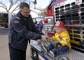 Edmonton fire Capt.  Dean Choma shows one-year-old Issa Hassan-Khaira how to operate a fire hose at the Get Ready in the Park event in Hawrelak Park Saturday, May 7, 2022. The event is to help people be prepared for emergencies.  Photo by Larry Wong