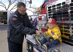 Edmonton fire Capt. Dean Choma shows one-year-old Issa Hassan-Khaira how to operate a fire hose at the Get Ready in the Park event in Hawrelak Park Saturday, May 7, 2022. The event is to help people be prepared for emergencies. Photo by Larry Wong