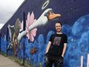 Mural artist Joshua Harnack in front of his artwork at 6316 106 St. in Edmonton.