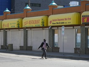 A pedestrian walks by some shuttered businesses in Edmonton's Chinatown on June 1, 2022.