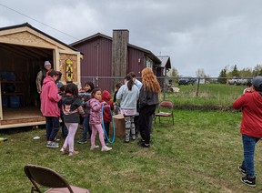 Young people stand in front of a shed that will house sports, games and handicraft equipment at Kapawe'no First Nation.