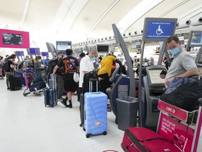 People wait in line to check in at Pearson International Airport in Toronto on Thursday, May 12, 2022. Canada has fallen behind in rankings for trade infrastructure, including airports, roads, ports and bridges.