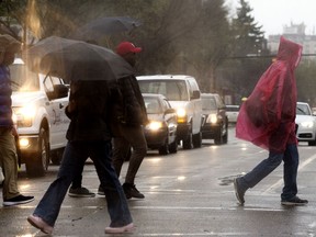 Pedestrians make their way through the rain near Whyte Avenue and 105 Street, in Edmonton Thursday May 19, 2022.