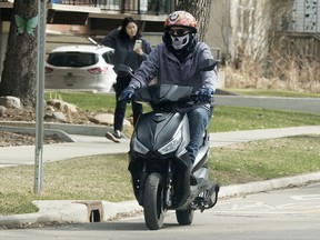 A motorist in a skull bandana and helmet, rides their electric scooter down the 83 Avenue bike lanes near 106 street, in Edmonton Monday April 19, 2021.