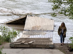 Edmonton Rowing Club president Maria Nanninga surveys the club's dock that has been secured with a cable to a land anchor on Thursday, June 16, 2022 in Edmonton. As the water rose on the North Saskatchewan River the club secured the dock but she is still worried as the river is  expected to rise. Pet owners should also avoid taking animals to the river as several have already been swept away.