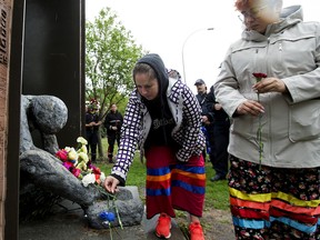 Edmontonians leave flowers at Edmonton's Homeless Memorial during a ceremony on June 15, 2022, to remember those who have died between 2019 and 2021 as a direct or indirect result of not having access to adequate housing.