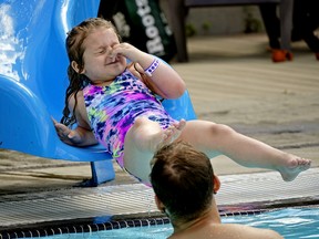 Aubree Richard, five, holds her nose as she slides into summer at Queen Elizabeth Outdoor Pool in Edmonton on June 22, 2022. The pool is the first of the outdoor pools to open in the city.