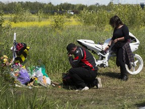 Adam Nicholson, left,, and Ann-Marie Thomas visit a memorial for their friend Nicole along Roper Road near 42 Street in Edmonton  on Monday, July 11, 2022. The accident occurred at around 2 a.m. Saturday when a 28-year-old female motorcyclist collided with a tree. A ghost bike was set up at the location.