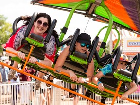 Postmedia reporter Lauren Boothby (left) rides the Cliff Hanger on the Midway at K-Days in Edmonton, on Saturday, July 23, 2022.