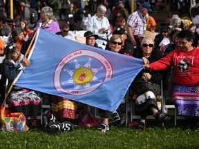 Indigenous community members hold a flag reading 