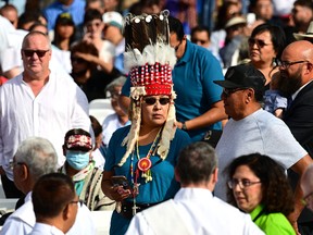 An indigenous woman wears a traditional headdress as she waits for a Holy Mass with the Pope at Commonwealth Stadium in Edmonton, western Canada, on July 26, 2022. - Pope Francis is visiting Canada for a chance to personally apologize to Indigenous survivors of abuse committed over a span of decades at residential schools run by the Catholic Church.