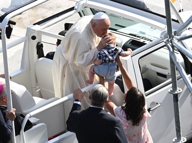 Pope Francis kisses a child as arrives for an open-air mass at Commonwealth Stadium in Edmonton, Canada, on July 26, 2022. - The Pope with be celebrating the feast of St. Anne, grandmother of Jesus, a day of particular reverence for Indigenous Catholics.